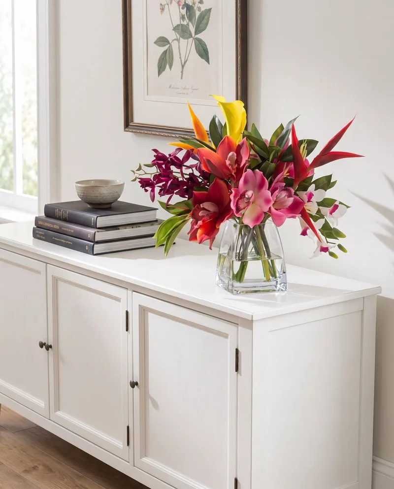 Orchids and Heliconia silk tropical arrangement on a sideboard