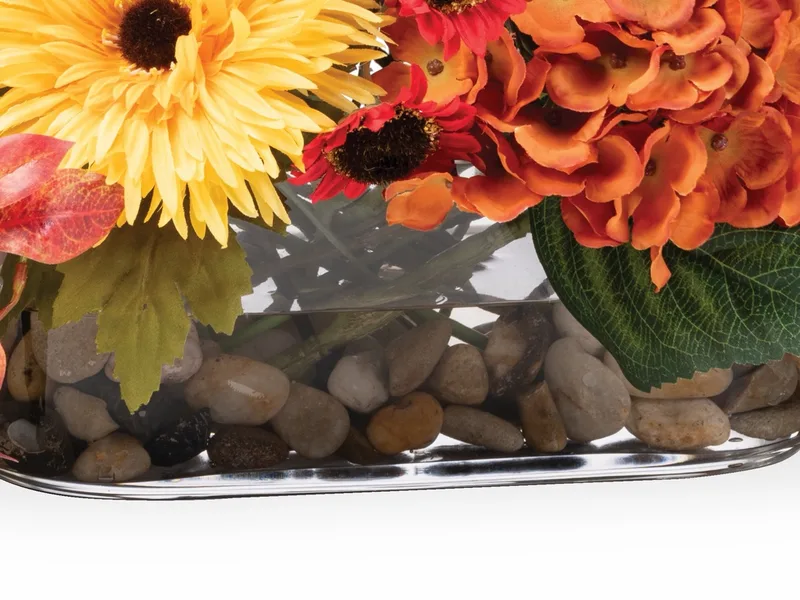 Oblong glass vase holding river stones under clear acrylic water