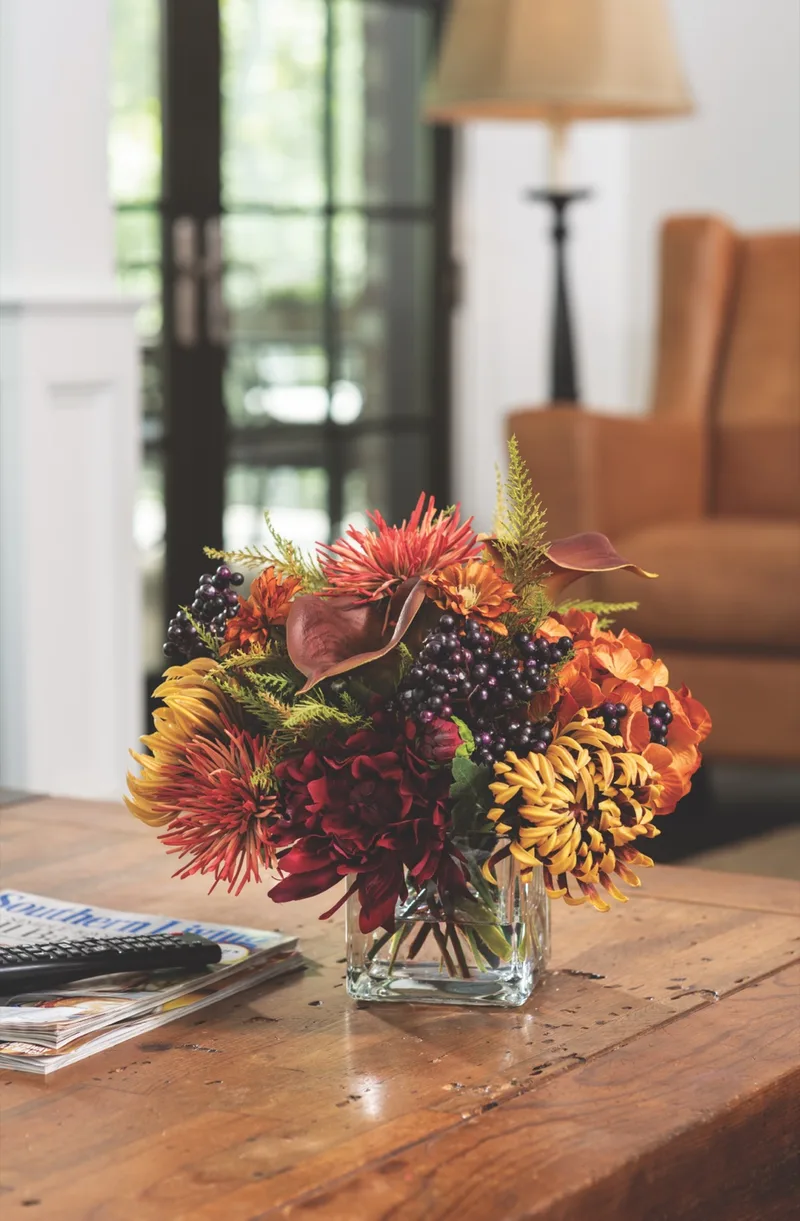 Spider mum and blackberries silk flower centerpiece on a wooden coffee table