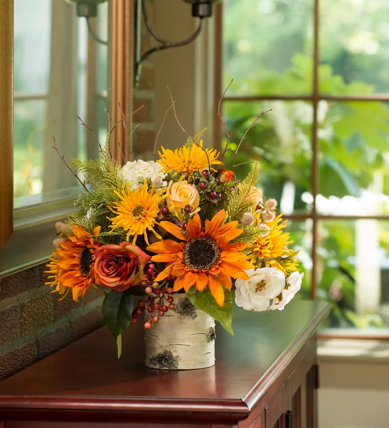 Autumn Sunrise silk flower centerpiece styled on a console table beside a window