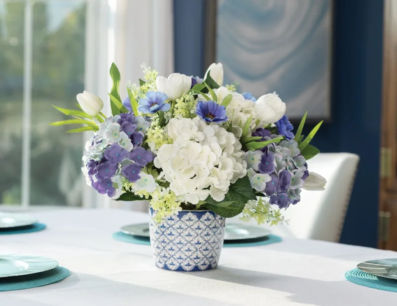 Blue and white silk flower centerpiece in a Delft pot on a set dining table