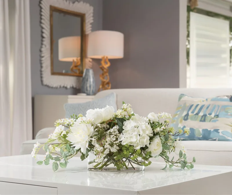 Simplistic Splendor white silk flower centerpiece on a white coffee table in a living room