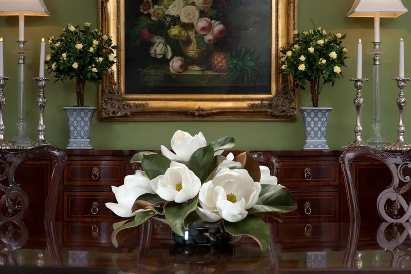 White silk magnolia centerpiece on a polished dining table in a formal dining room