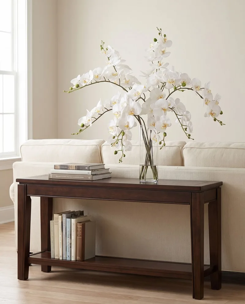 Grand Phalaenopsis silk orchid arrangement in White on a console table behind a sofa