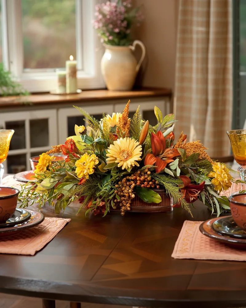 Zinnia, gerbera and lily silk flower centerpiece low on a set dining table