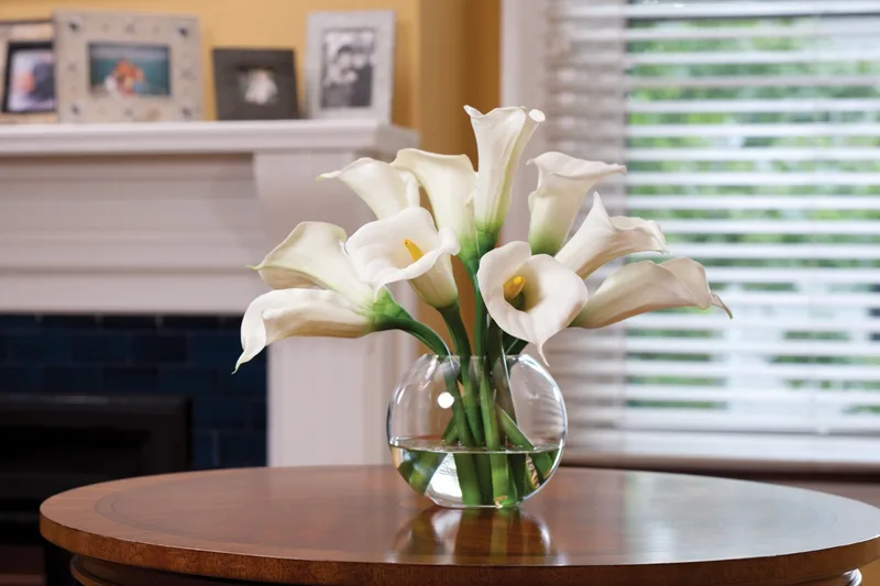 White silk calla lily centerpiece on a round side table in front of a fireplace