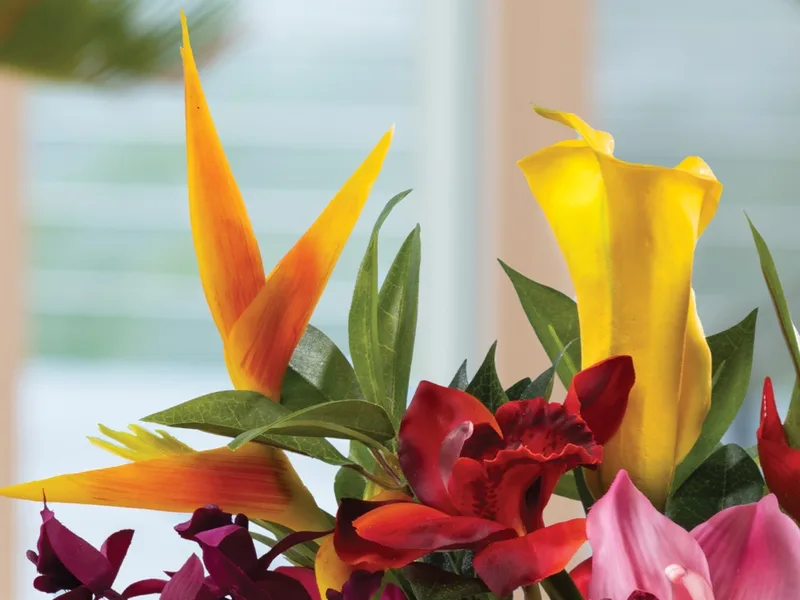 Silk heliconia and tropical blooms in orange, red and gold with green foliage