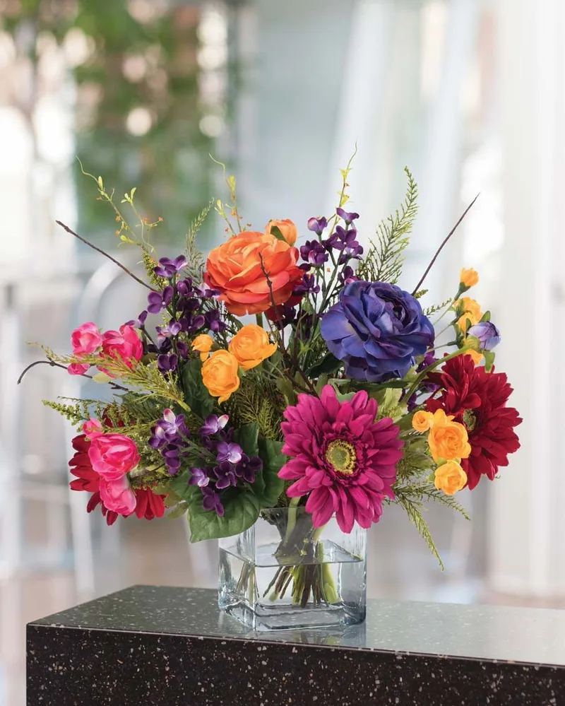 Festive Mood silk flower centerpiece in a glass cube vase on a dark stone tabletop