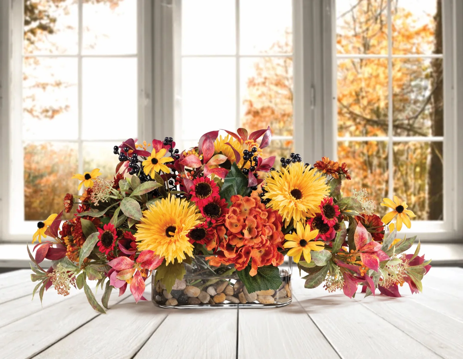Silk hydrangea, zinnia and daisy autumn centerpiece on a white plank table by an autumn window