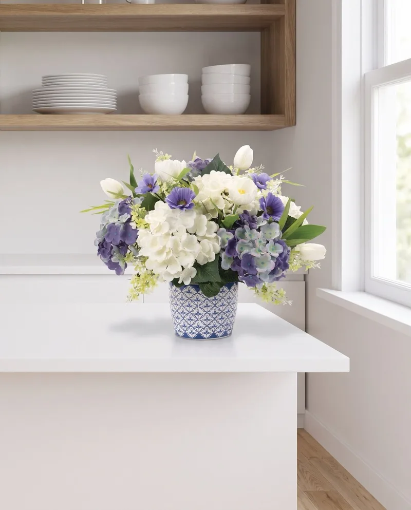 Blissful Blue and White silk flower centerpiece on a white kitchen counter below open shelves
