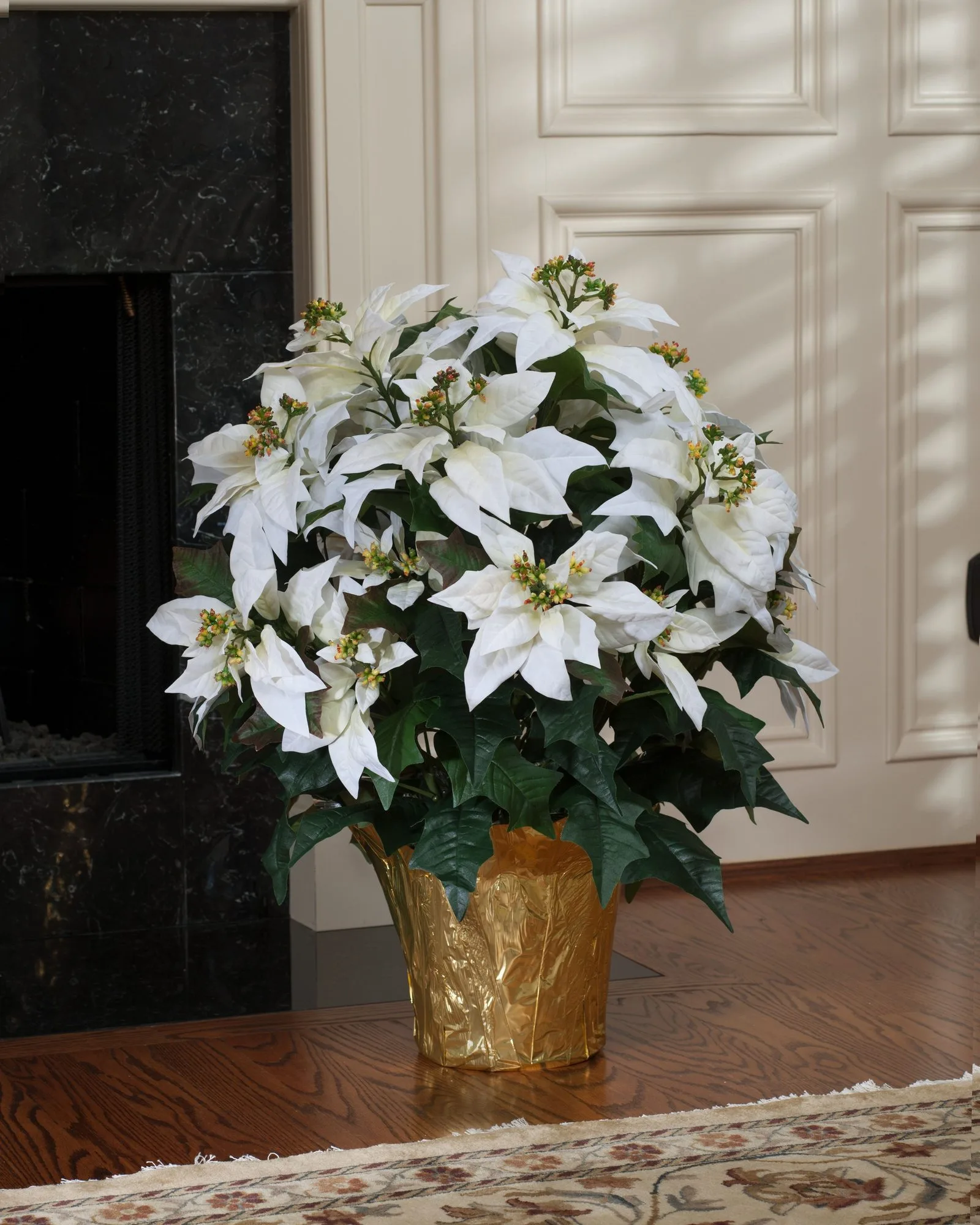 White Premier Silk Poinsettia beside a marble fireplace