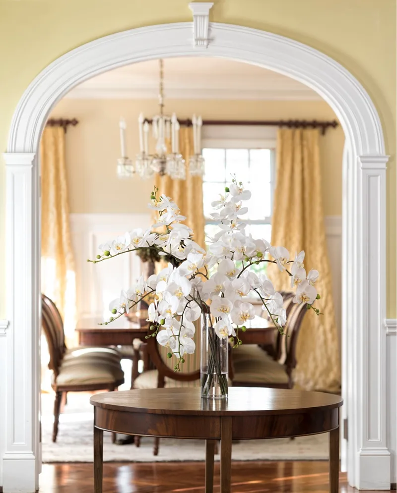 White silk phalaenopsis orchid arrangement on a round table framed by an archway